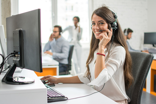 Young friendly operator woman agent with headsets working in a call centre.